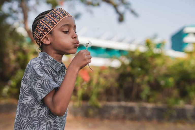 cute-african-boy-blowing-dandelion-outdoor-at-city-park-e1657720778729