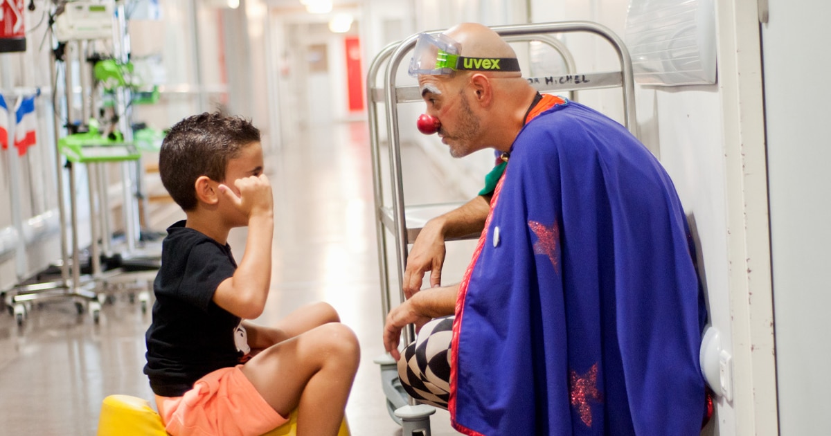 Clown professionnel en chambre d’hôpital avec un enfant
